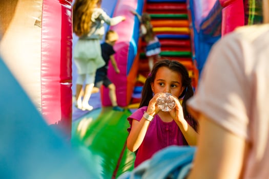 little girl drinks water on an inflatable trampoline photo