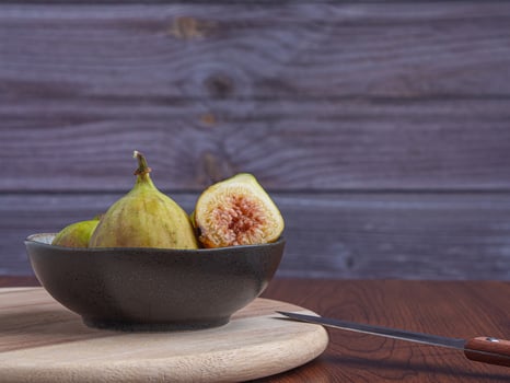 Ripe figs fruit on the cement floor with a wooden wall background. High Vitamins fruit. Space for text. Healthy fruits and healthcare concept photo