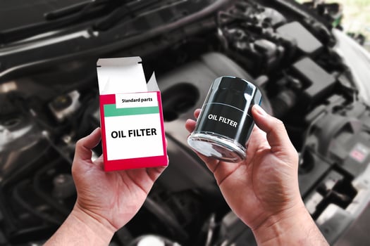 A car mechanic hand is unpacking a new oil filter to replace it. New oil filter in the hands of an car mechanic , Car maintenance concept photo