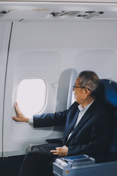 Attractive Asian male passenger of airplane sitting in comfortable seat while working laptop and tablet with mock up area using wireless connection. Travel in style, work with grace. photo