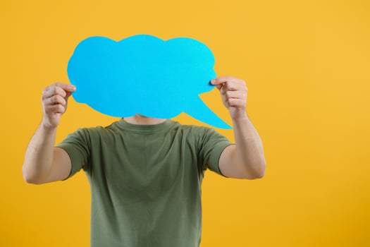 Handsome man holding blank speech bubble sign isolated on yellow studio background photo