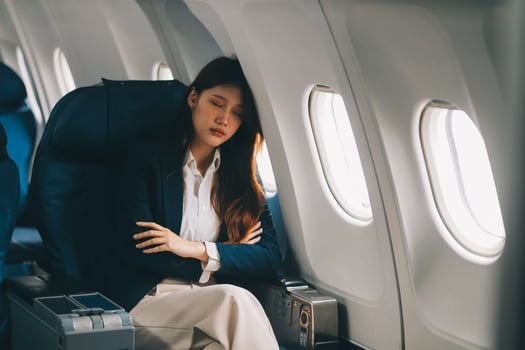 Photo of a frustrated woman sitting on an airplane with her head in her hands. Asian woman sitting in a seat in airplane