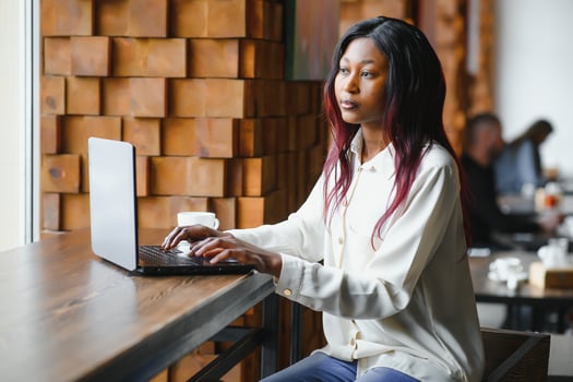 Young woman siting at cafe drinking coffee and working on laptop photo