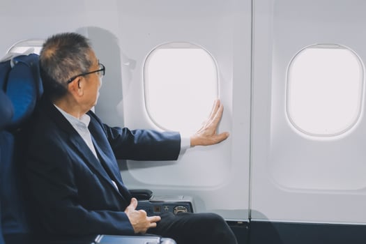 Attractive Asian male passenger of airplane sitting in comfortable seat while working laptop and tablet with mock up area using wireless connection. Travel in style, work with grace. photo