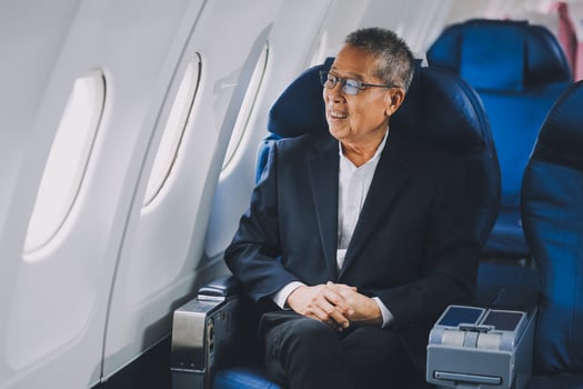 Attractive Asian male passenger of airplane sitting in comfortable seat while working laptop and tablet with mock up area using wireless connection. Travel in style, work with grace. photo