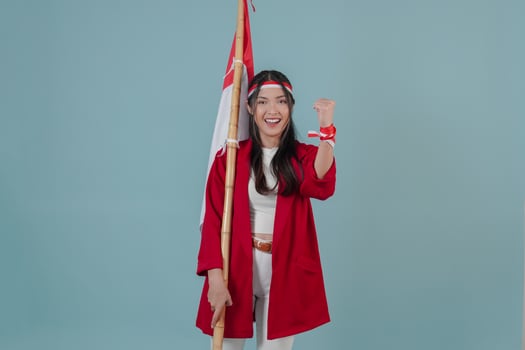 Cheerful Indonesian woman holding a flag while raising fist gesture. photo