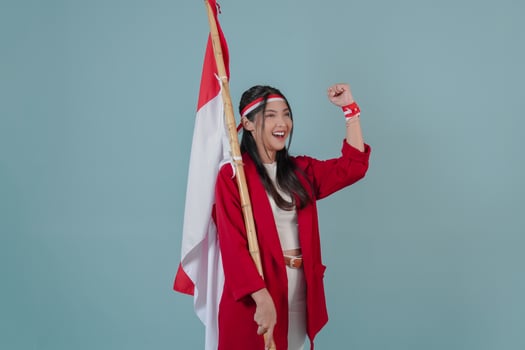 Cheerful Indonesian woman holding a flag while raising fist gesture. photo