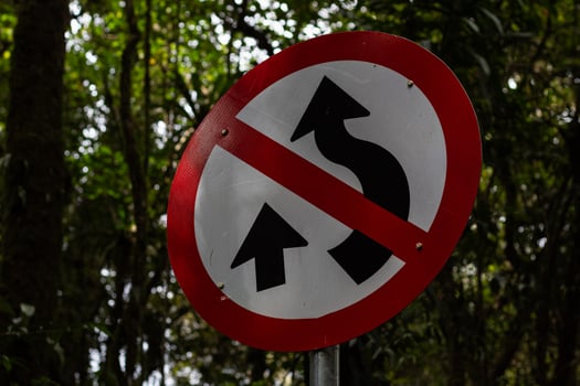 The winding road sign is made of metal and is red and white in color. photo