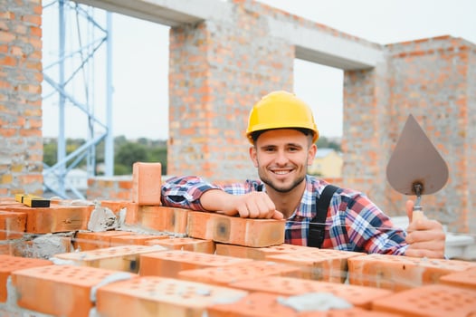 Yellow colored hard hat. Young man working in uniform at construction at daytime. photo