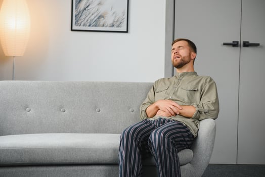 Man suffering stomach ache sitting on a couch in the living room at home. photo