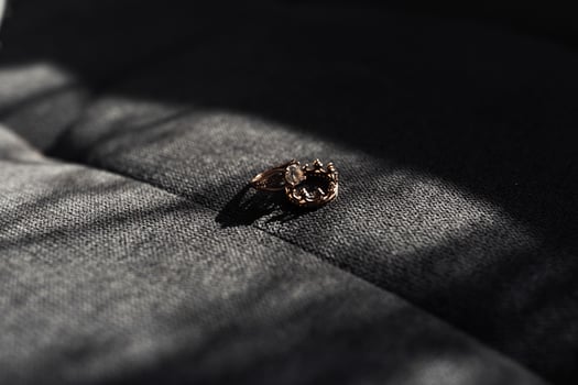 A ring is sitting on a gray surface. The ring is made of gold and has a design on it photo