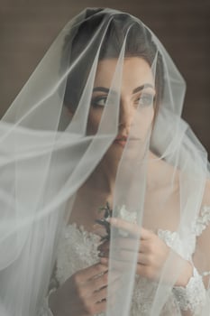 A woman is wearing a veil and holding a flower. The veil is white and covers her face, creating a sense of mystery and elegance photo