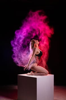 Young woman posing with multicolored particles in the air photo