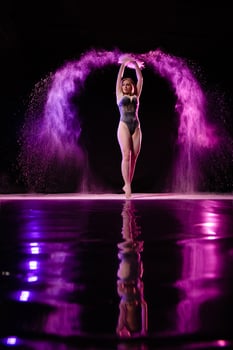 Young slim woman posing with purple particles sprayed in the air photo