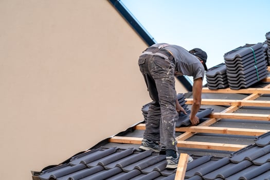 roofer installs a fired ceramic tile on the roof of family house photo