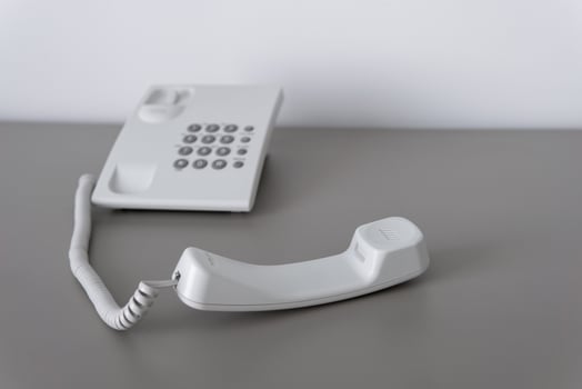 Modern white landline office phone with a hook. Technical support concept. No answer. Closeup white phone , office phone on the desk. Closeup white phone , office phone on the desk. photo