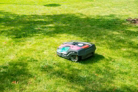 Modern robot lawn mower on green grass in park promenade, spa town Podebrady photo