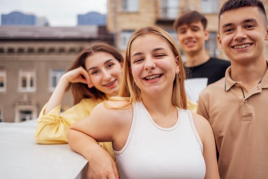 Cute female teenager laughs and looks at the camera with her friends on the roof of the house. Funny students relax, walk and have fun together. photo