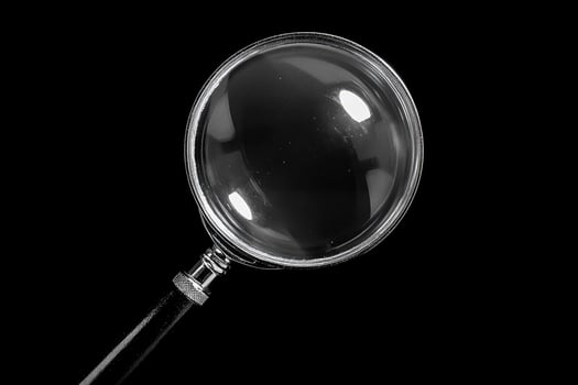 Magnifying glass on black background exploring the unknown photo