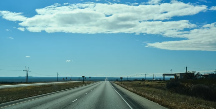 Straight road stretching into the distance against a blue sky with white clouds, New Mexico photo
