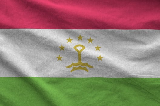 Tajikistan flag depicted on folded wavy fabric of old cloth photo