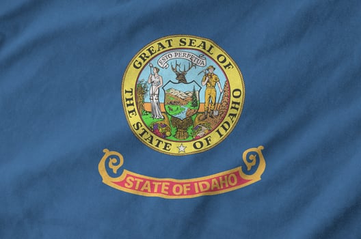 Idaho US state flag depicted on folded wavy fabric of old cloth photo