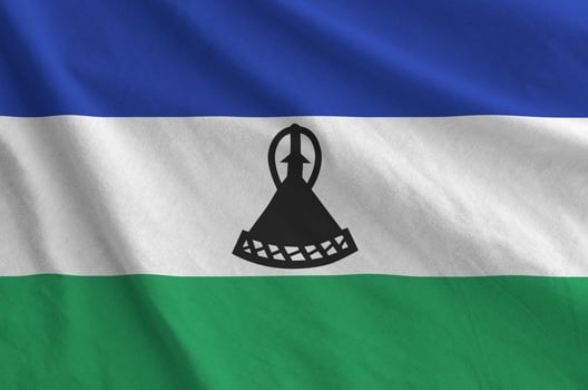 Lesotho flag depicted on folded wavy fabric of old cloth photo