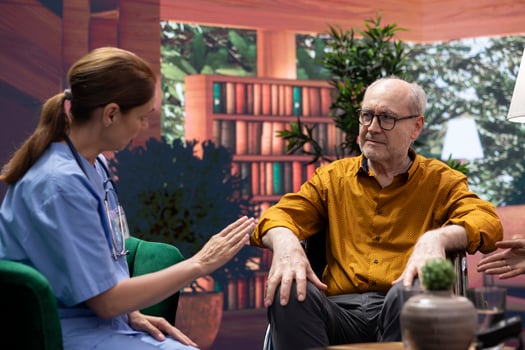Senior woman comforting her husband with impairment in wheelchair, elderly couple listening to guidance and professional advice from medical assistant at home. Chronic illness. photo