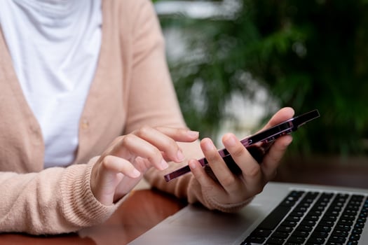 A close-up image of a woman is using her smartphone while working remotely at a table in a garden. photo