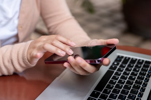 A cropped image of a woman using her smartphone while working remotely at a table outdoors. photo
