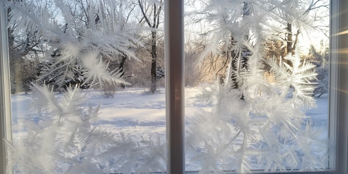 Frost Patterns on Window Glass Overlooking Snowy Winter Landscape photo