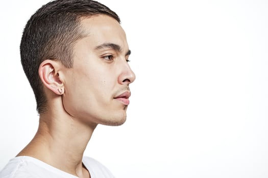 Young man with short hair and a piercing looking off to the side photo