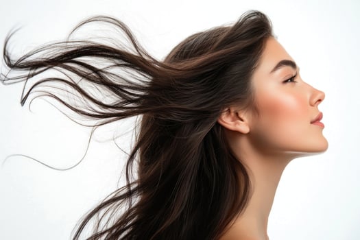 A profile portrait of a young brunette woman with flowing hair on a white background. photo