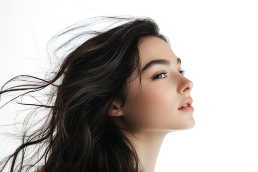 Profile shot of a beautiful young brunette with wind-swept hair against a white backdrop. photo