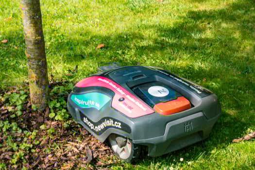 Modern robot lawn mower on green grass in park promenade, spa town Podebrady photo