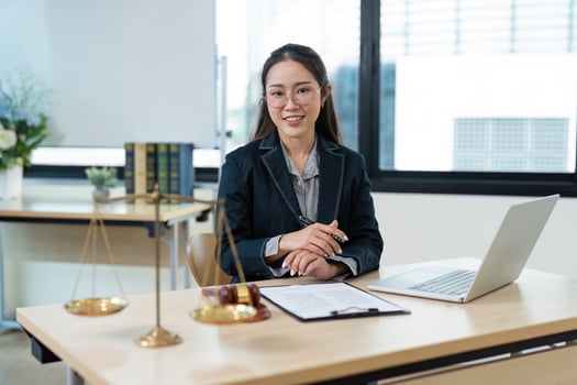 Confident Female Lawyer Working at Desk with Legal Documents and Laptop in Modern Office Setting photo