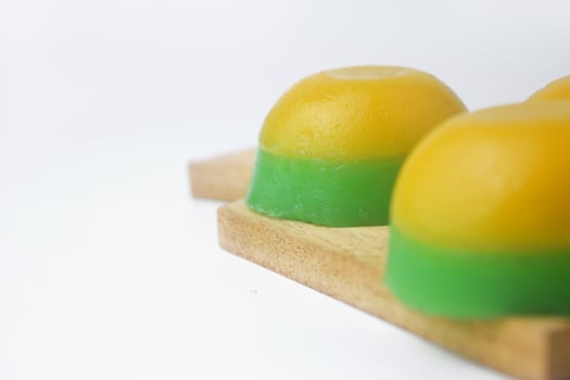 Yellow green round layered cake on a wooden coaster is an Indonesian food photo