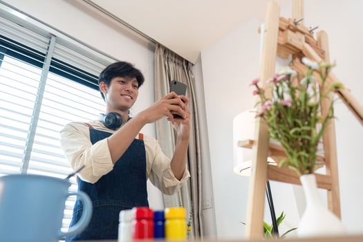 Young Artist Taking a Photo of His Artwork in a Bright Studio with Natural Light and Modern Decor