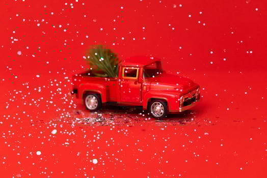 Red toy truck with Christmas fir branch in its trunk. photo