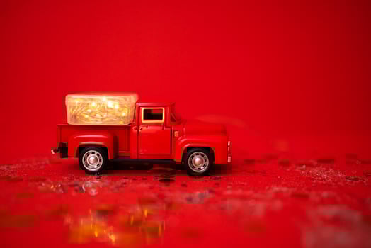 Red toy truck with Christmas balls and fir branch in its trunk. photo