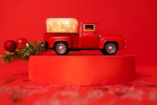 Red toy truck with Christmas fir branch in its trunk. photo