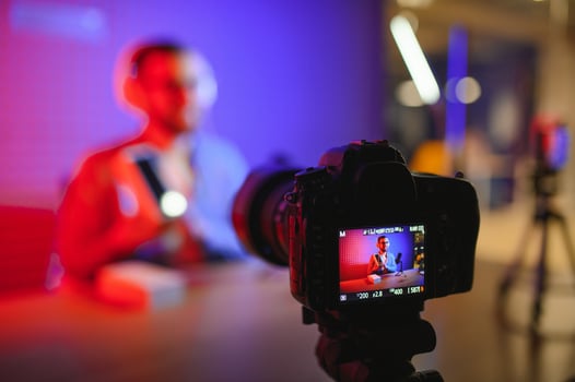 Male technology blogger recording blog or vlog review of new smartphone, showing it on camera at home studio. Blogging, Work from Home concept. Selective focus. Web Banner photo
