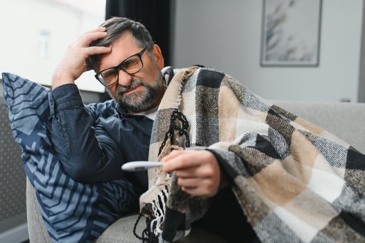 Portrait of sick senior man with thermometer posing at home photo
