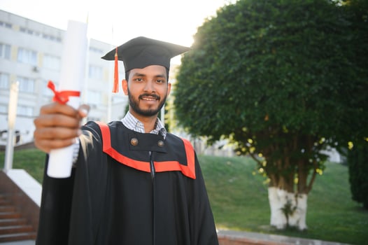 Portrait of indian handsome male graduate in graduation robe. photo