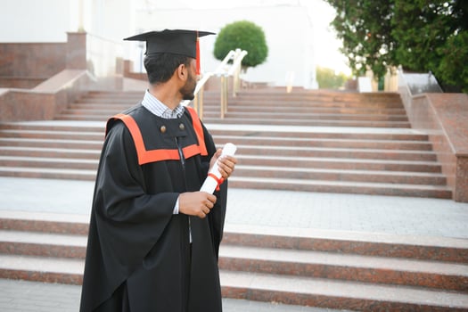 Portrait of indian handsome male graduate in graduation robe. photo