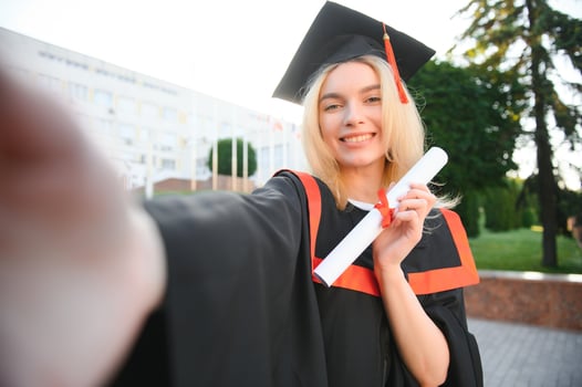 Portrait enthusiastic female college student graduate in cap and gown celebrating, holding diploma. photo