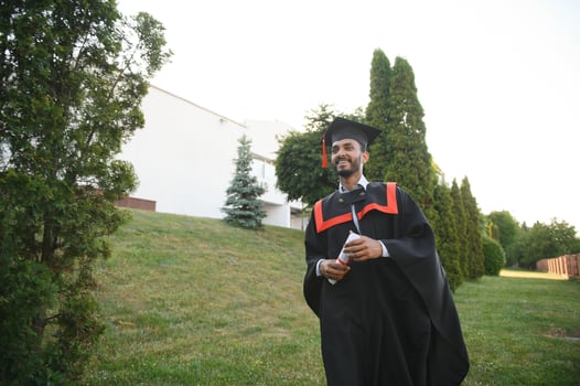 Handsome indian graduate in graduation glow with diploma. photo