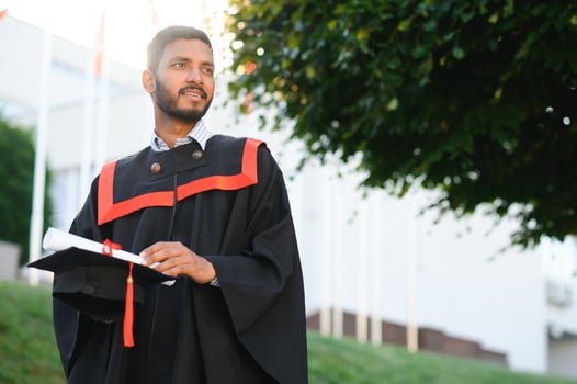 Portrait of indian handsome male graduate in graduation robe. photo