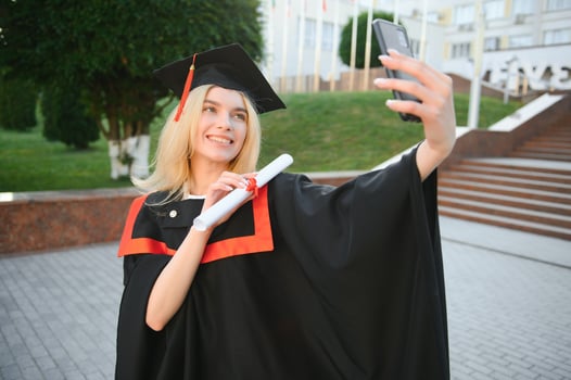 Female graduating student in bachelor robe taking selfie on her graduation day photo