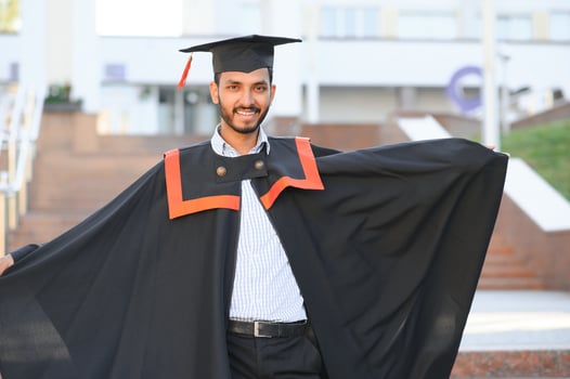 Portrait of indian handsome male graduate in graduation robe. photo